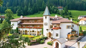 Un hotel con una torre central, varios balcones con jardineras y un jardín bien cuidado.