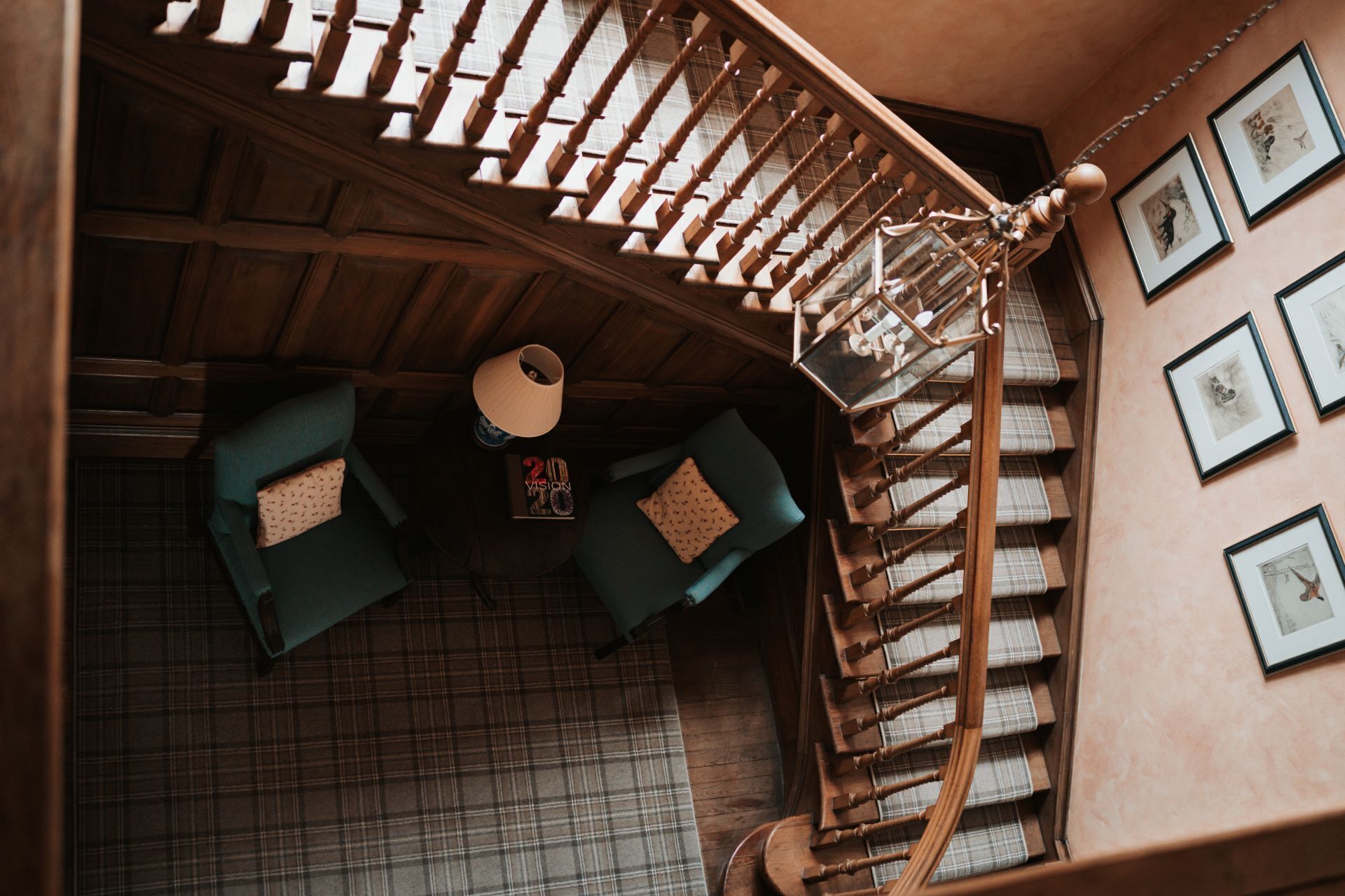 A staircase with wooden balusters, a round table with a lamp, and a sofa with patterned cushions.