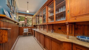 A wooden kitchen with a herringbone floor pattern, a wooden bar counter, and a large window with a view of greenery. - Dunkeld House - Luxury Cottages (Dunkeld)