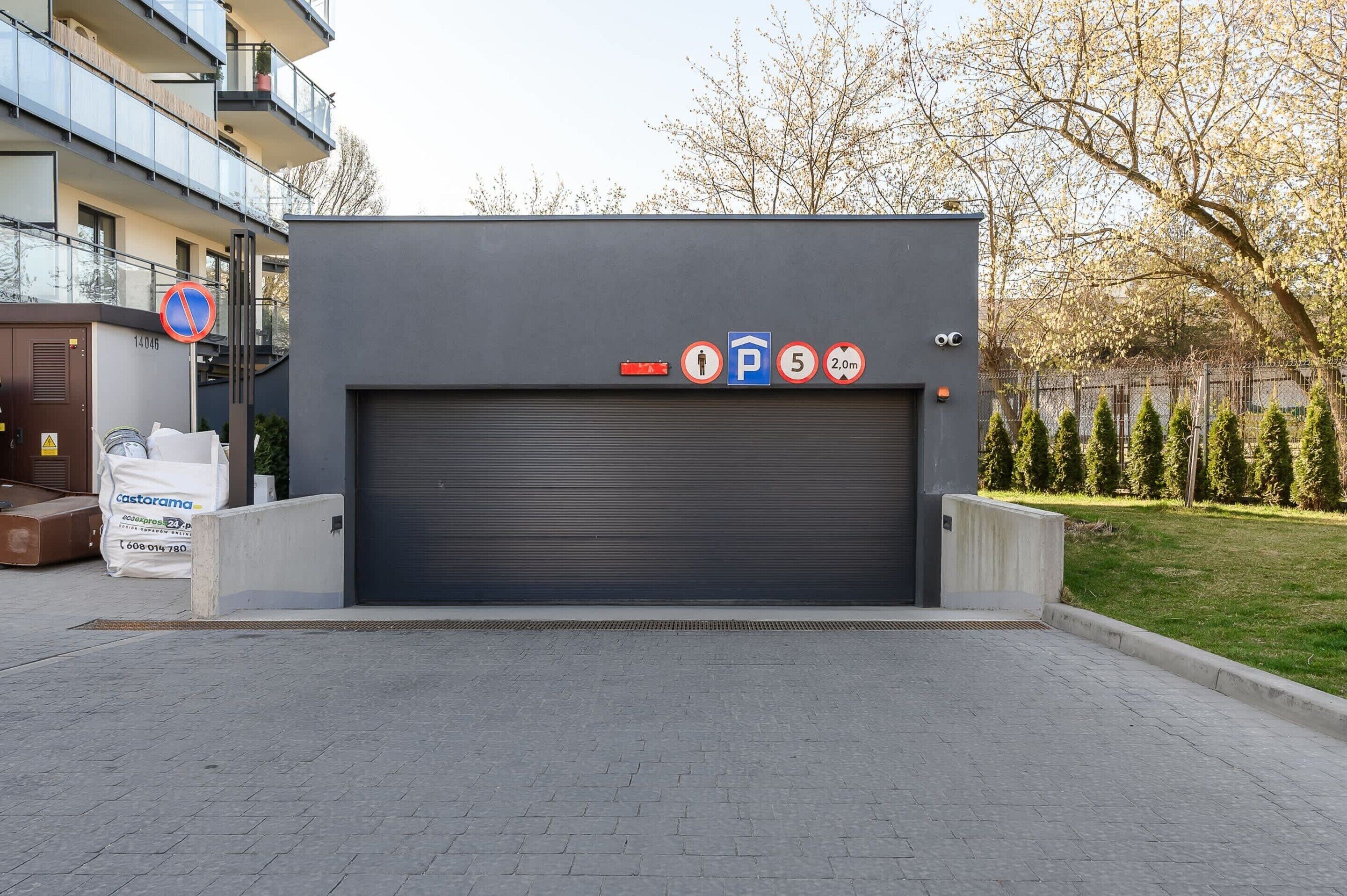 A modern building with a closed garage door, a no parking sign, and a disabled parking sign.