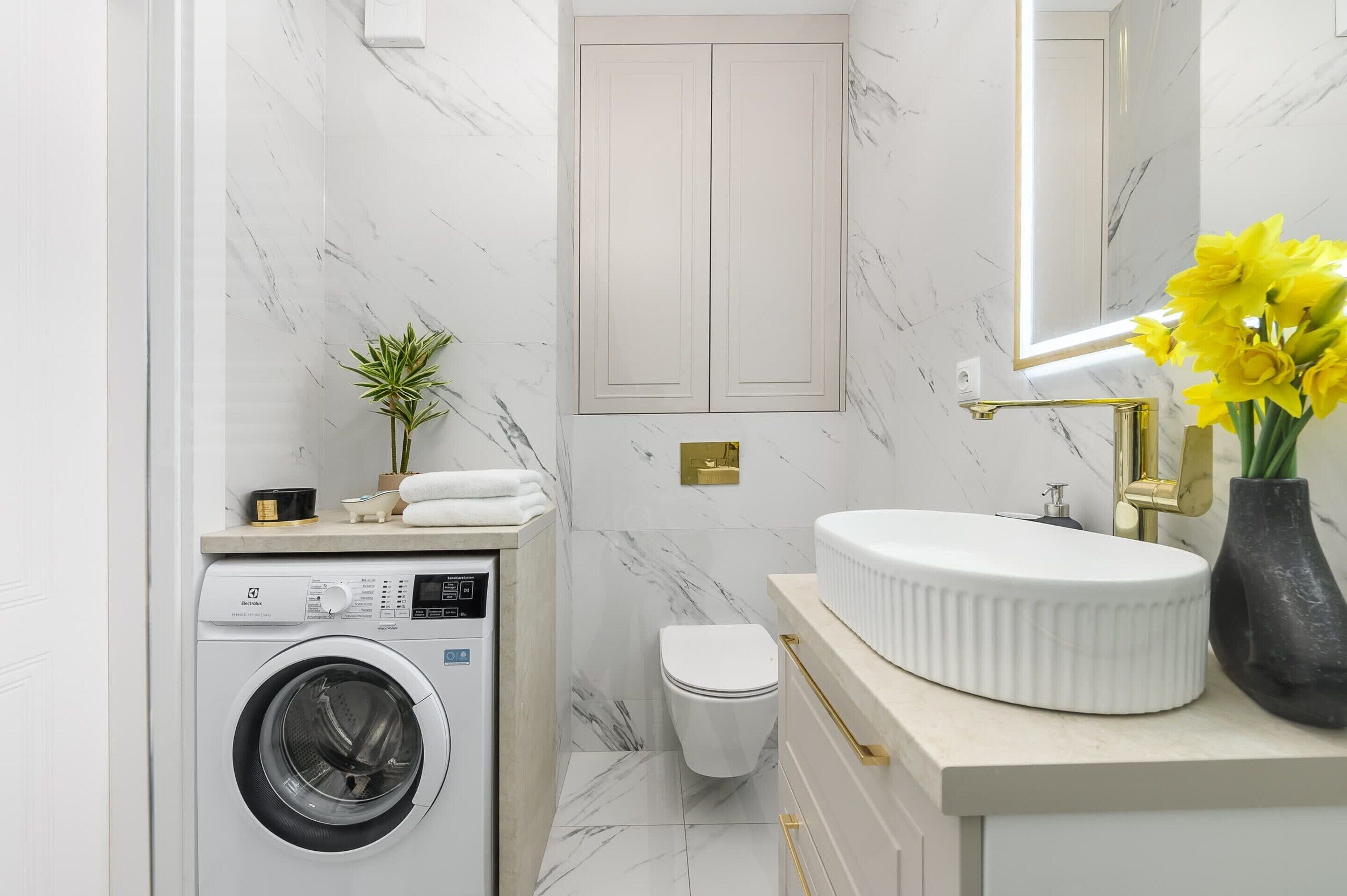 A modern bathroom with a washing machine, toilet, and sink.