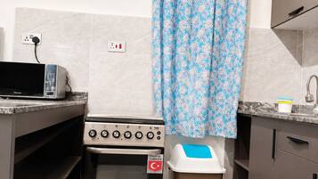 A kitchen with a stove, a trash bin, and a power outlet.