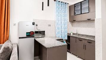 A compact kitchen with a refrigerator, microwave, and a small island.