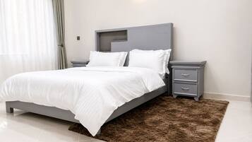 A modern bedroom with a bed, bedside tables, and a wall-mounted light fixture.