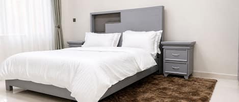 Un dormitorio moderno con una cama, mesitas de noche y una lámpara de pared.
