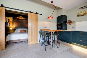 Un dormitorio moderno con cama, escritorio y silla. Hay una puerta corrediza que da a otra habitación.
