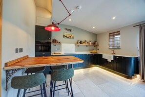 Una cocina moderna con una barra de madera, taburetes de bar y una lámpara colgante roja.