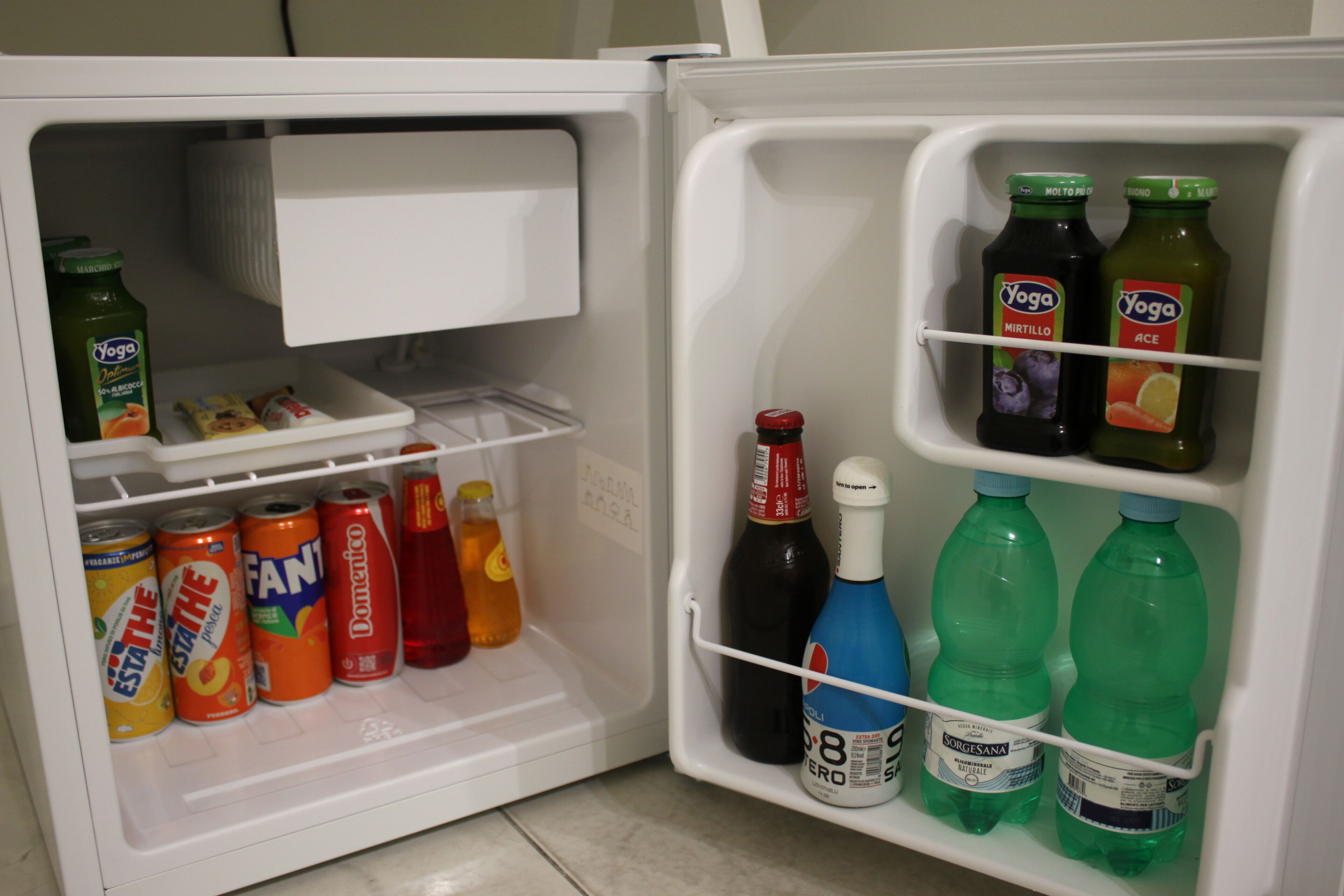 Un refrigerador abierto con diversas bebidas y refrescos.