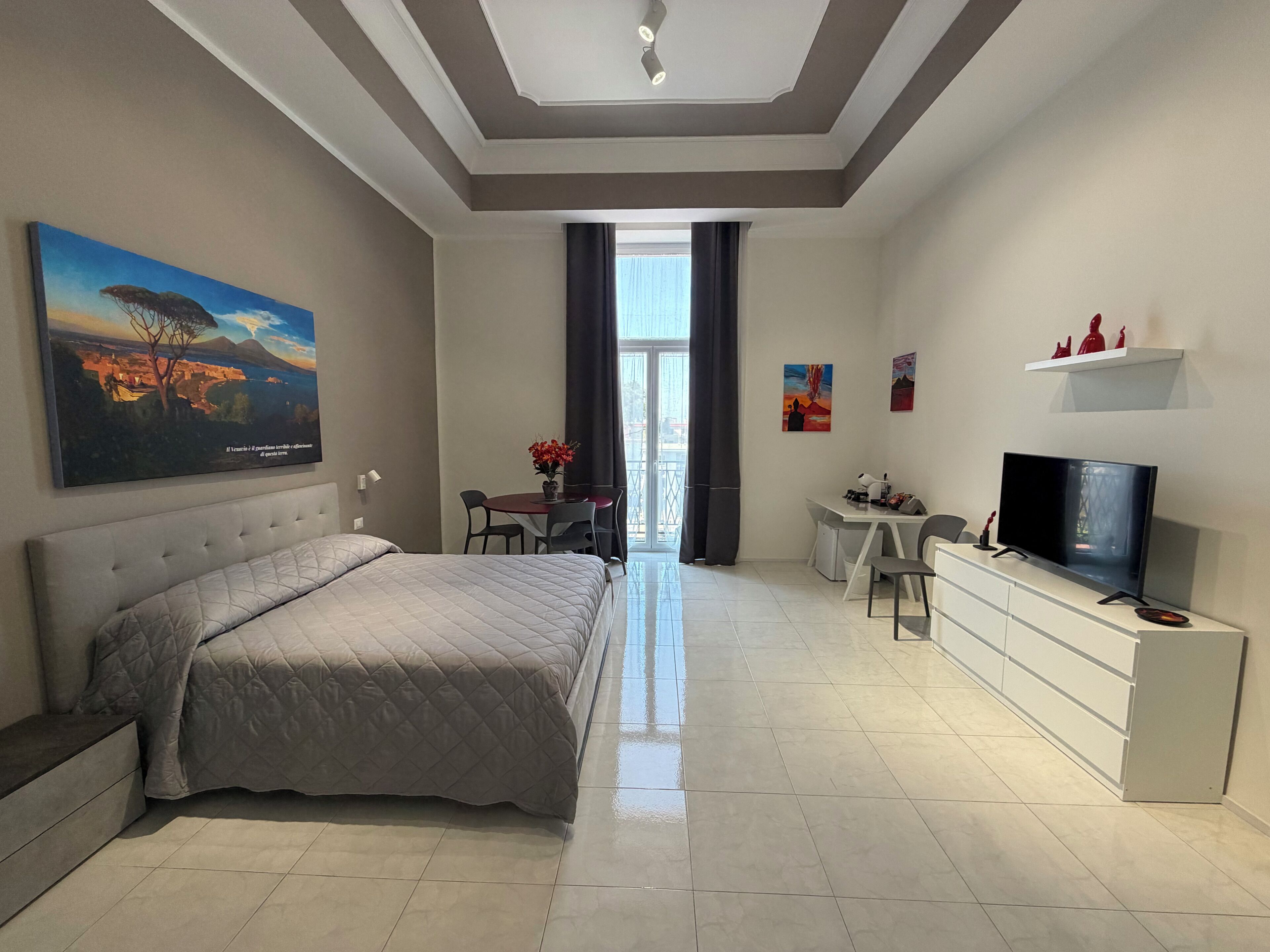 Un dormitorio moderno con una cama grande, un escritorio y un televisor.