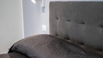 Una cama con cabecera, una lámpara de pared y un enchufe.