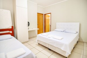 A hotel room with a single bed, a bedside table, a wooden wardrobe, and a door leading to another room. - Casa Del Rey (Pirenópolis)