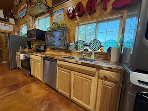 A kitchen with wooden cabinets, stainless steel appliances, and a window overlooking a garden.