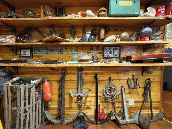 A wooden shelf with various nautical items, including anchors, a ship model, and decorative shells.