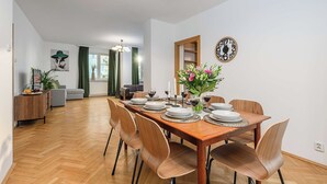 Uma área de refeições com uma mesa de madeira posta para seis pessoas, rodeada por seis cadeiras.