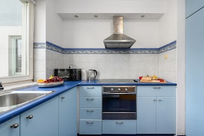 Eine Küche mit blauer Arbeitsplatte, einer Edelstahl-Spüle, einer Mikrowelle, einem Wasserkocher und einem Toaster.