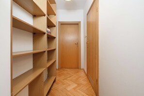 Ein enger Flur mit Holzbögen und Regalen an einer Seite sowie einer Holztür am Ende.