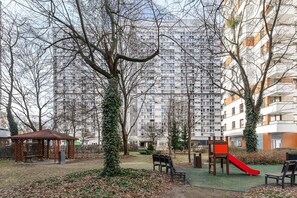 Ein Park mit Spielplatz, Bänken und einem Kiosk.
