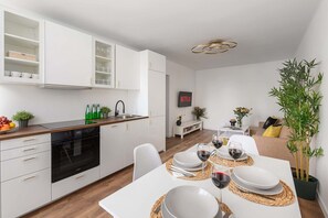 Eine moderne Küche mit weißen Schränken, einem eingebauten Backofen und einem Essbereich mit Tisch für zwei Personen.
