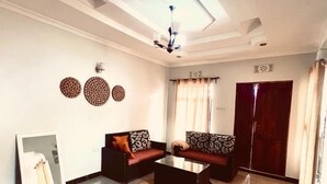 A living room with a sofa set, a coffee table, a mirror, and a patterned rug. - Ngorongoro Haven & Safari Stride (Karatu)