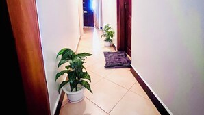 A hallway with a potted plant, a rug, and a door on the right. - Ngorongoro Haven & Safari Stride (Karatu)