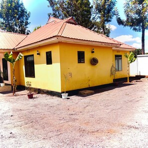 Um edifício amarelo com telhado vermelho, uma pequena janela e uma porta.