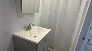 Un baño con un lavamanos blanco, un espejo y una cortina de ducha.