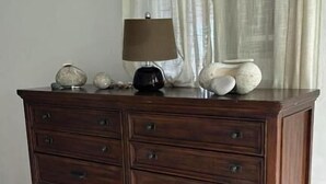 Un aparador de madera con cajones, una lámpara y objetos decorativos encima.