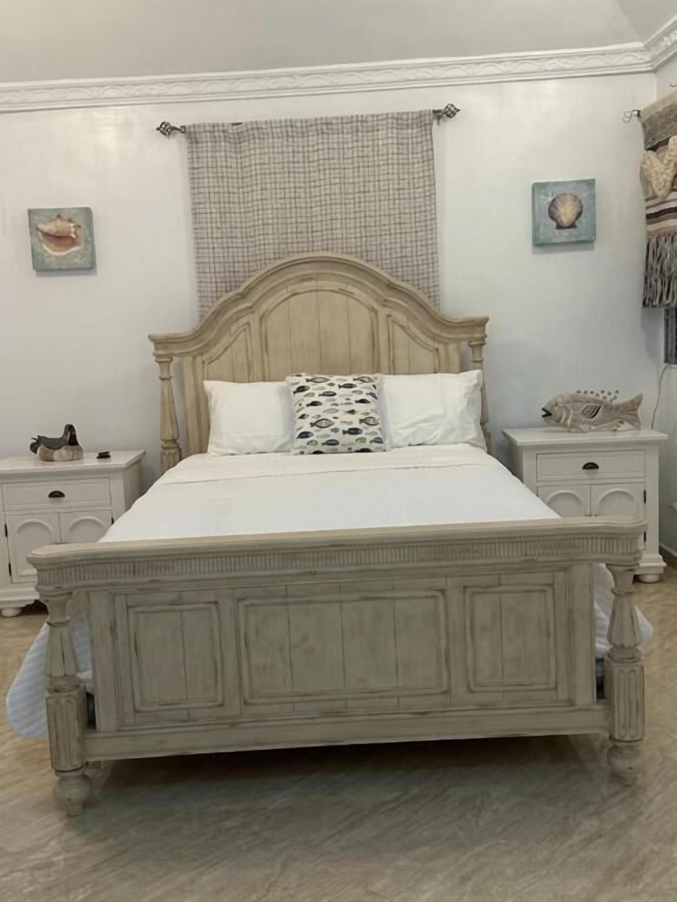 Ein Bett mit einem Holz-Kopfteil, zwei Nachttische und einem karierten Vorhang.