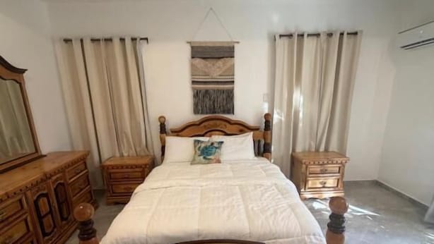 Un dormitorio con una cama de madera, un aparador y un tapiz colgado.