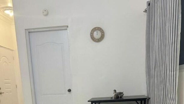 Una habitación con una puerta blanca, una pequeña mesa con taburetes y un radiador.