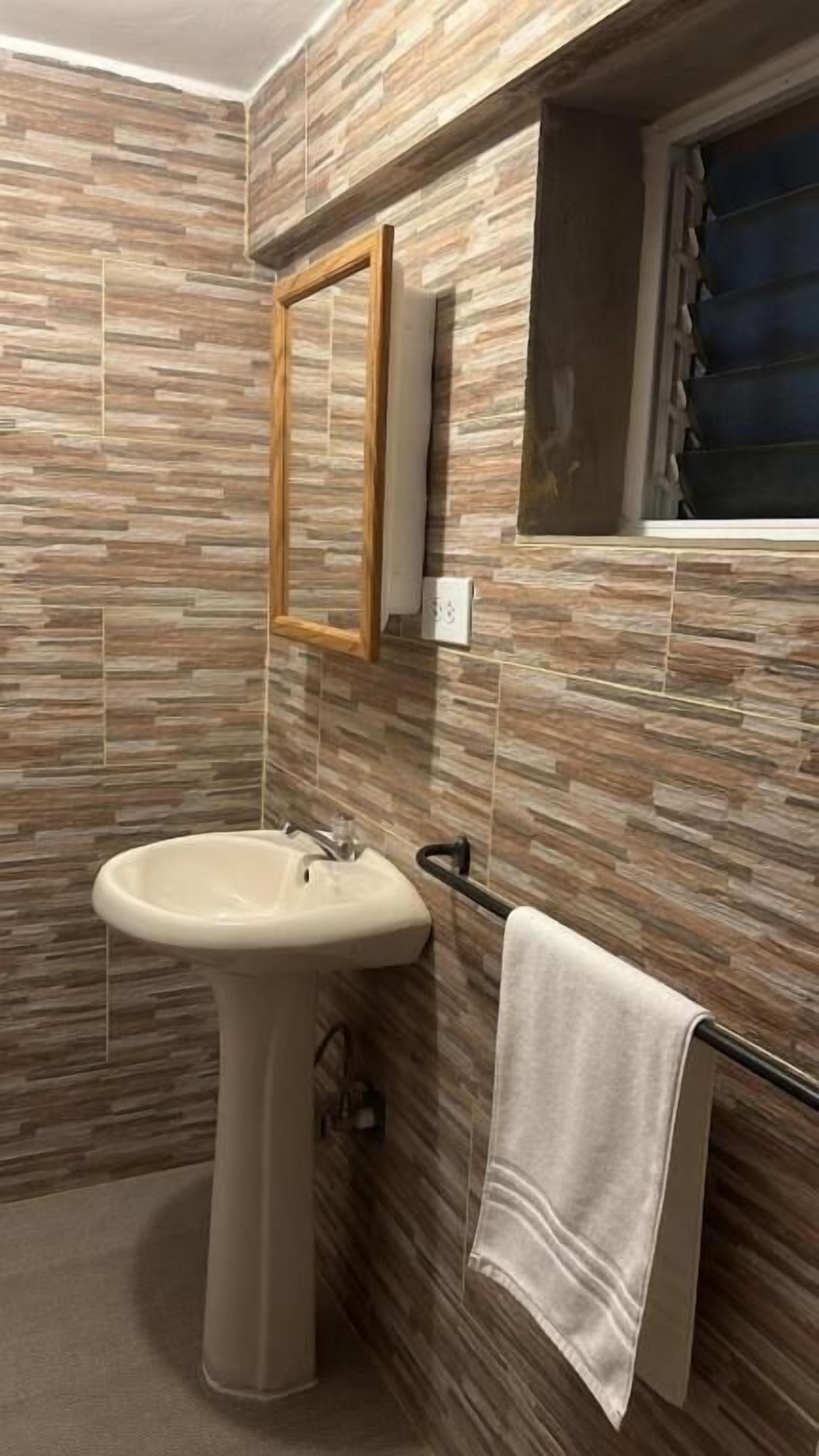Un bagno con un lavandino su piedistallo, un porta asciugamani e uno specchio.