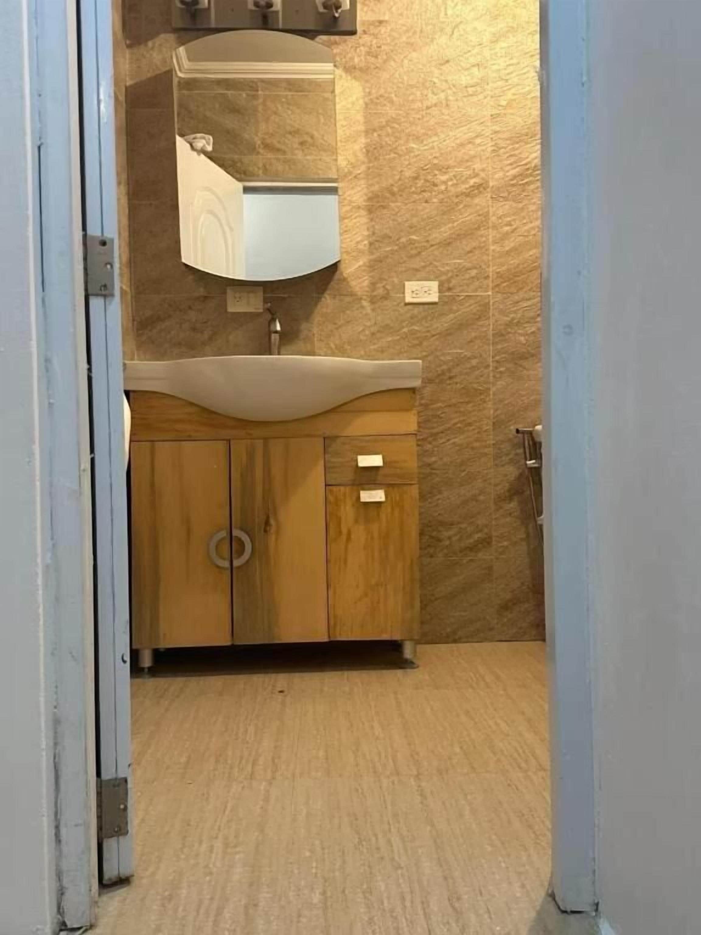 A bathroom with a wooden vanity, a sink, and a mirror.