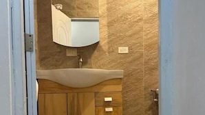 Un baño con tocador de madera, lavabo y espejo.