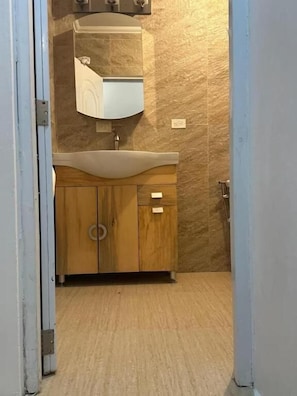 Un baño con tocador de madera, lavabo y espejo.