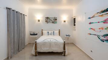 A bedroom with a bed, bedside tables, a wall-mounted artwork, and a curtain.