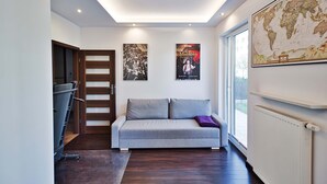 A modern interior with a grey sofa, a wooden door, and two posters on the wall. - City Apartment for 6 Guests (Warsaw)
