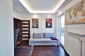 A modern interior with a grey sofa, a wooden door, and two posters on the wall. - City Apartment for 6 Guests (Warsaw)