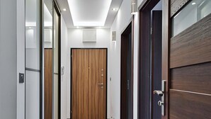 A hallway with wooden flooring, a sliding glass door, and a dark wooden door. - City Apartment for 6 Guests (Warsaw)