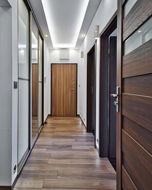 A hallway with wooden flooring, a sliding glass door, and a dark wooden door. - City Apartment for 6 Guests (Warsaw)