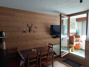 A wooden interior with a table, chairs, a mounted deer head, and a television. - Apartment in Saint-Lary Village (Saint-Lary-Soulan)