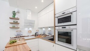 Eine moderne Küche mit weißen Schränken, einer Holz Arbeitsplatte und einem eingebauten Backofen.
