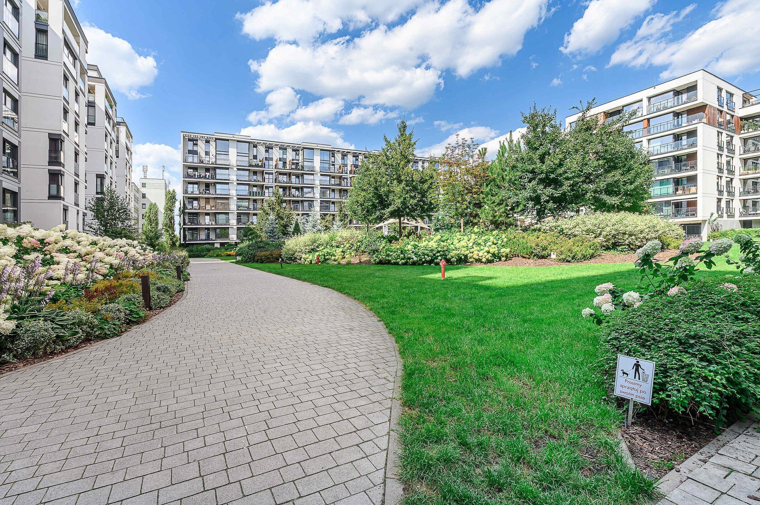 A residential building with a paved pathway and a well-maintained garden.