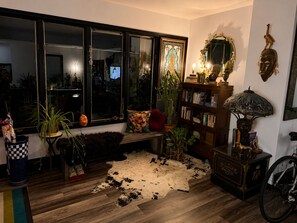 A cozy living room with a large window, a bookshelf, a leather rug, and a bicycle. - Spacious 3BR Home in Heart of Montclair – Walkable, Near NYC & Newark Airport (Montclair)
