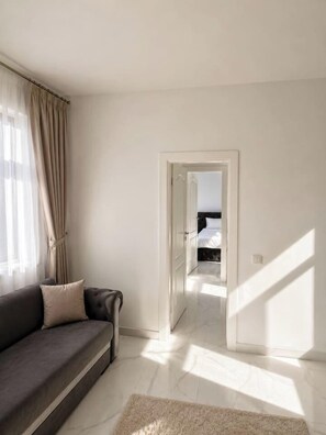 A modern living room with a sofa, a rug, and a doorway leading to a bedroom. - Modern Luxury Apartment • Heart of the City (Bucharest)