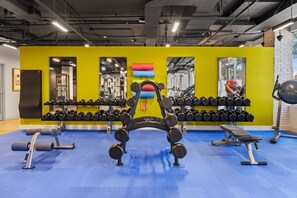 Ein Fitnessstudio mit Krafttrainingsgeräten, Spiegeln und einem blauen Gummoboden.