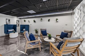 A modern lounge area with seating arrangements, a polished floor, and decorative wall elements. - Modern Tempe 1BR • AC + Pool + Gym • 5 Min to ASU (Tempe)