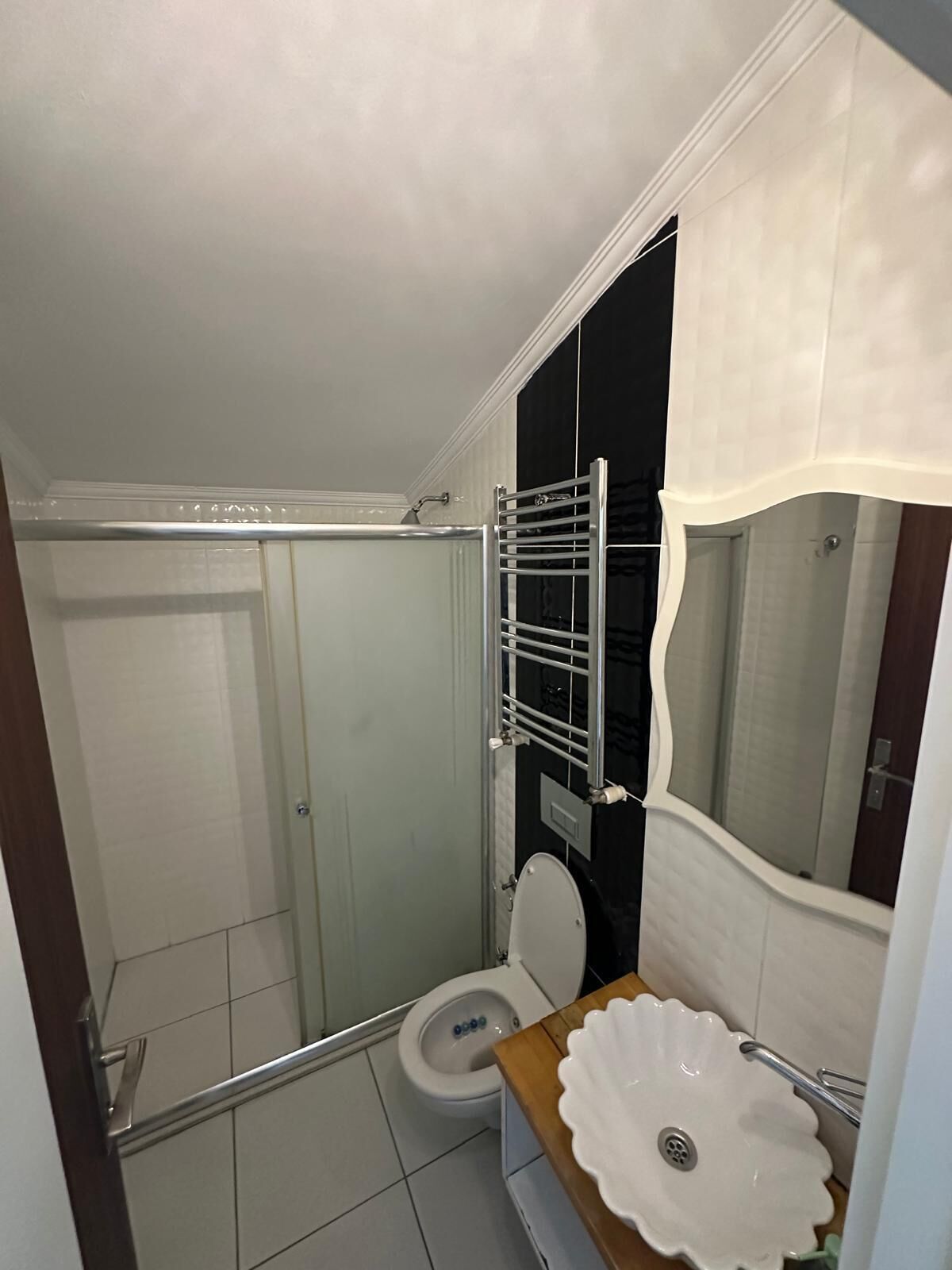Un baño con inodoro, cabina de ducha y lavabo con lavamanos decorativo.