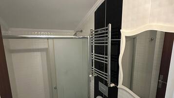 Un baño con inodoro, cabina de ducha y lavabo con lavamanos decorativo.