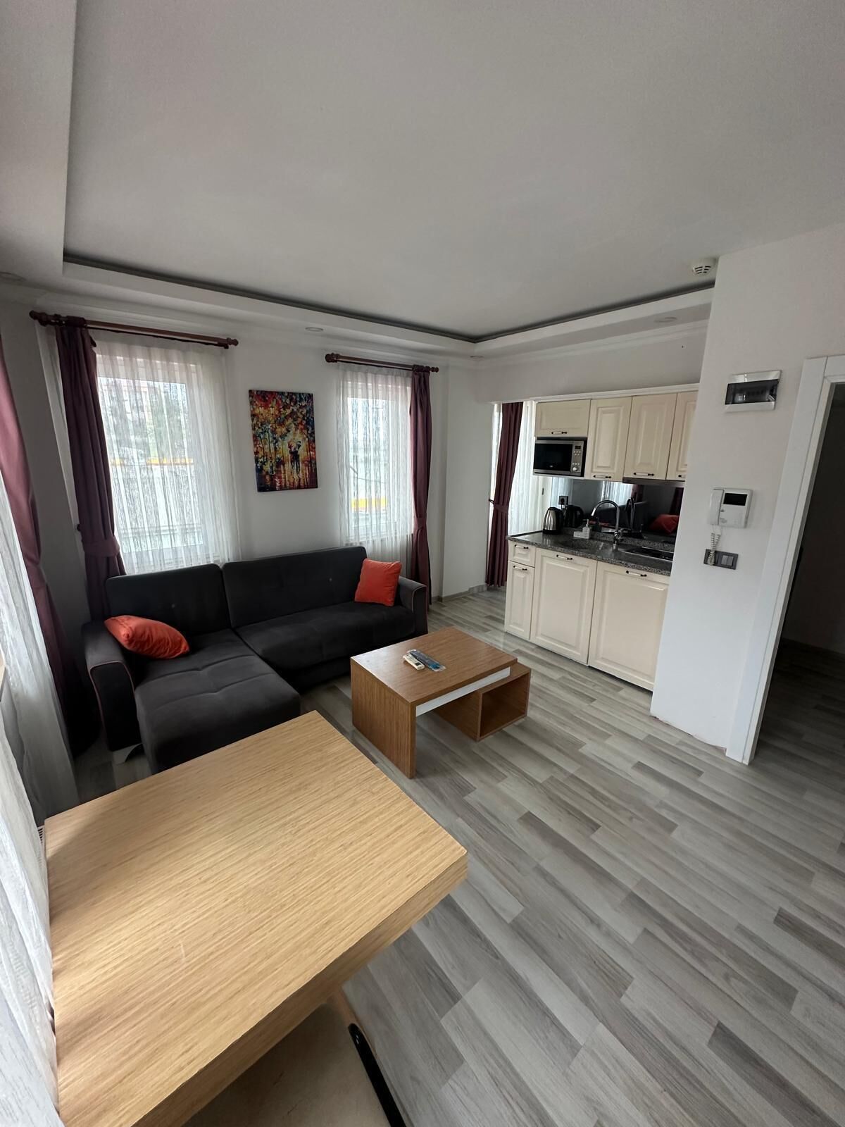 Una sala de estar moderna con un sofá, una mesa de centro y una zona de cocina con armarios y electrodomésticos.