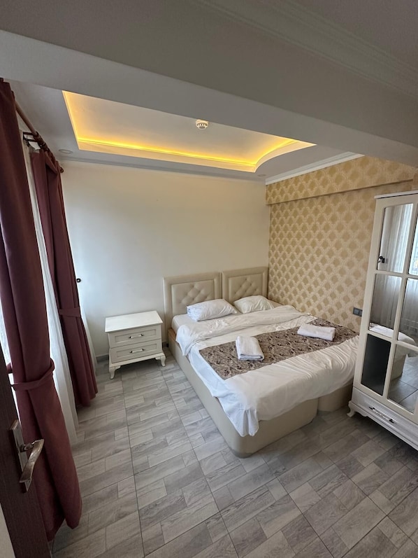 A bedroom with a large bed, bedside tables, a wardrobe, and a ceiling light.
